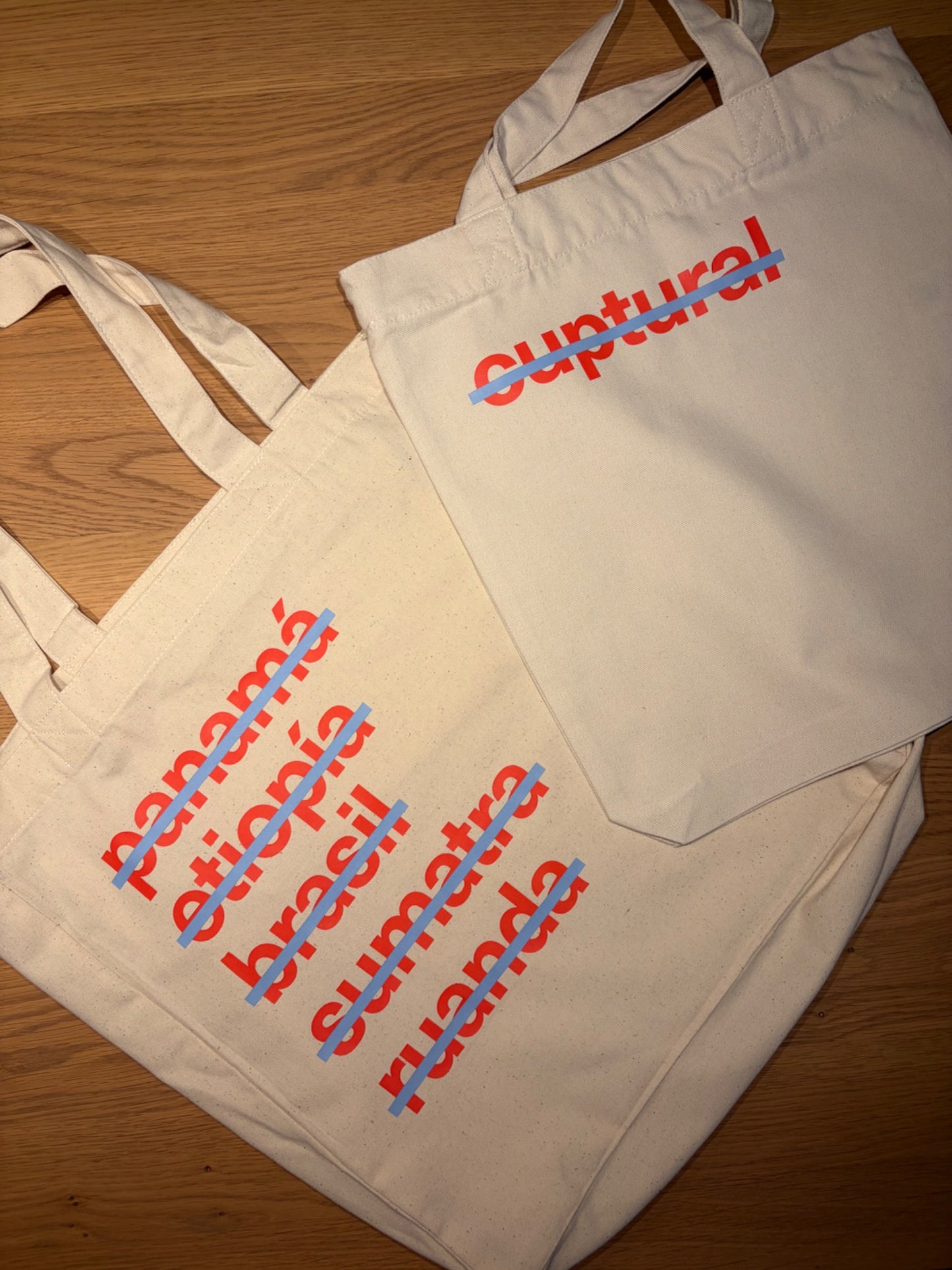 Dos tote bags cuptural con diseño de logo y orígenes